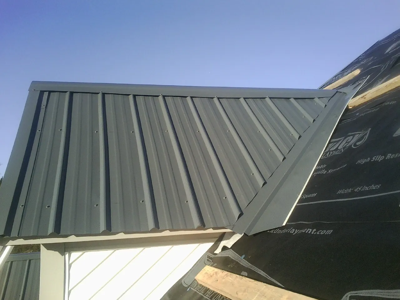 Gray metal roof panels going on over a garage gable in Clarence