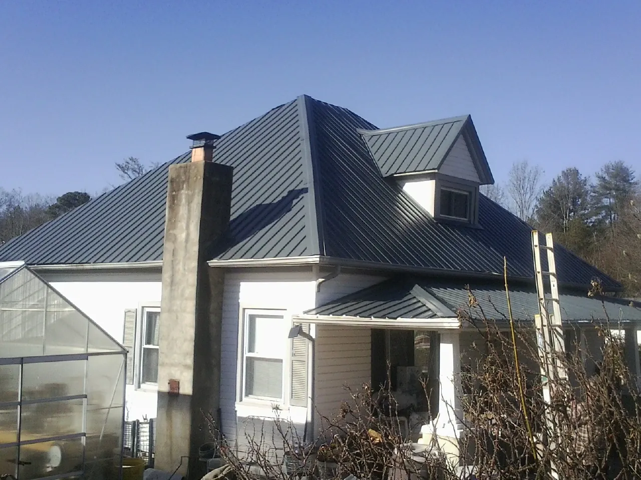 Dark blue standing seam metal roof on a white farmhouse with dormer — Slate & Tile Roof Repair by Roofing Brothers in Clarence