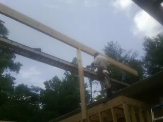 Carpenter setting a ridge beam over a new addition frame — Ice Dam Removal by Roofing Brothers in Clarence