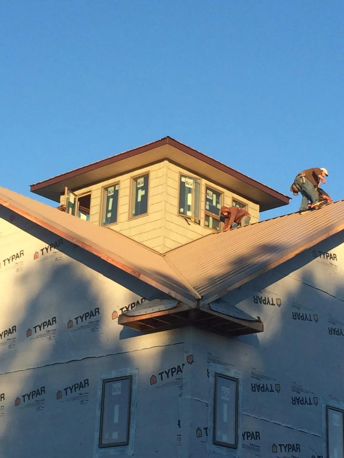 Roofers working around a rooftop cupola on a new metal roof at sunset — Roof Waterproofing in Clarence by Roofing Brothers